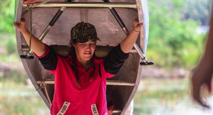 a student portages a canoe on an outward bound gap year expedition 